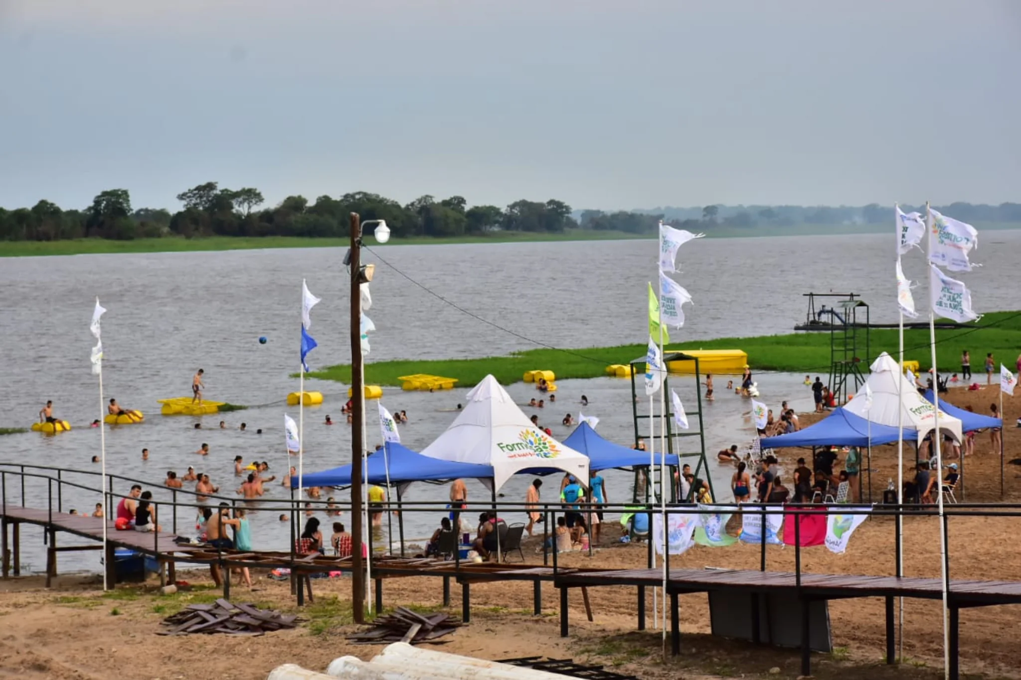 Personas disfrutando y nadando en la Laguna Herradura durante la Fiesta Nacional de la Corvina de Río en Formosa.